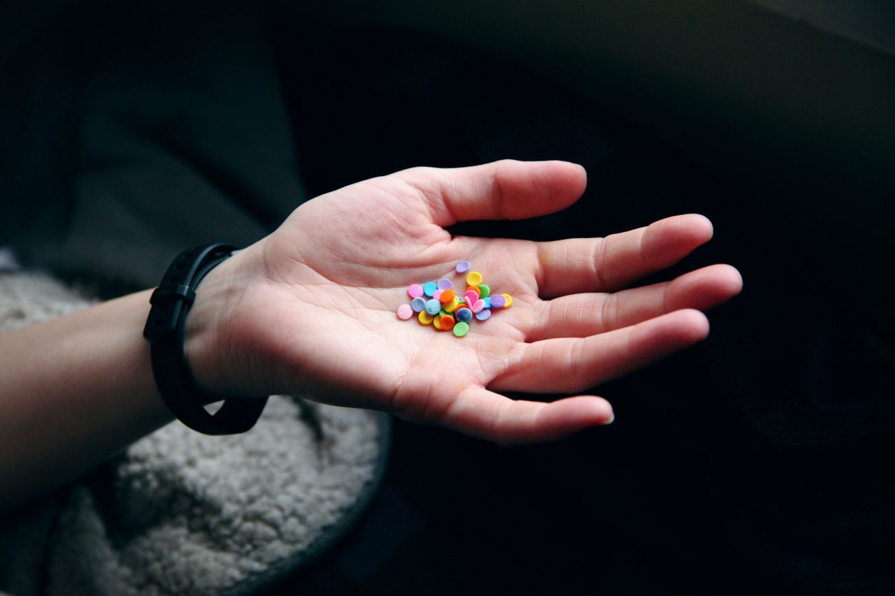 A hand holding colorful confetti against a dark background, showcasing vibrant pastel hues.