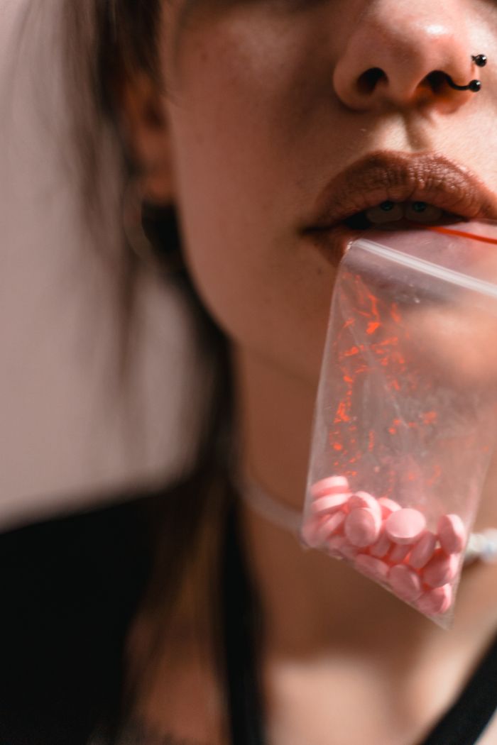 A close-up of a person holding a bag of pills, exploring themes of substance use and healthcare.